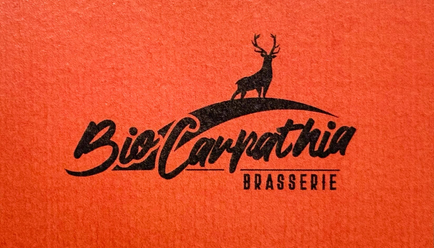 Logo-ul Brasserie Bio Carpathia aplicat pe o suprafață texturată portocalie