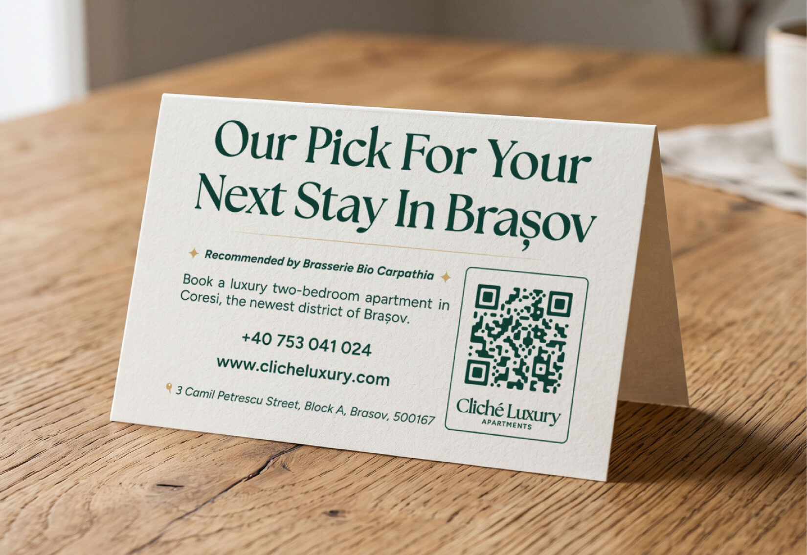 Cardul de recomandare Cliché Luxury pe masa unei cafenele, cu cod QR și datele de contact