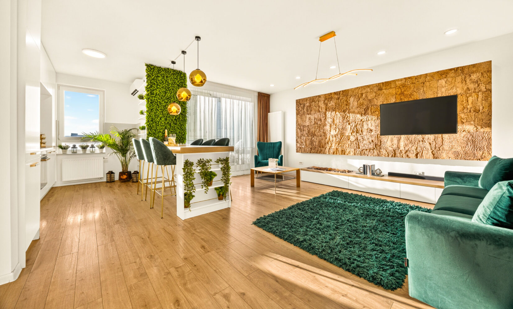 Livingul apartamentului Cliché Luxury, cu peretele din plută, bucătăria deschisă și canapeaua din catifea verde
